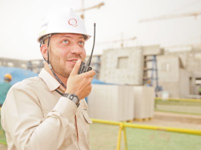 Man Wearing White Hard Hat Holding 2 Way Radio