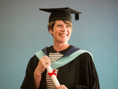 graduate holding scroll smiling