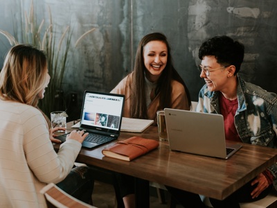 three people sitting around a table smiling