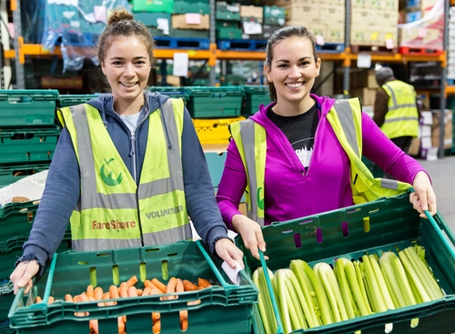 Jennie and Eleanor holding veg crates at FareShare warehouse